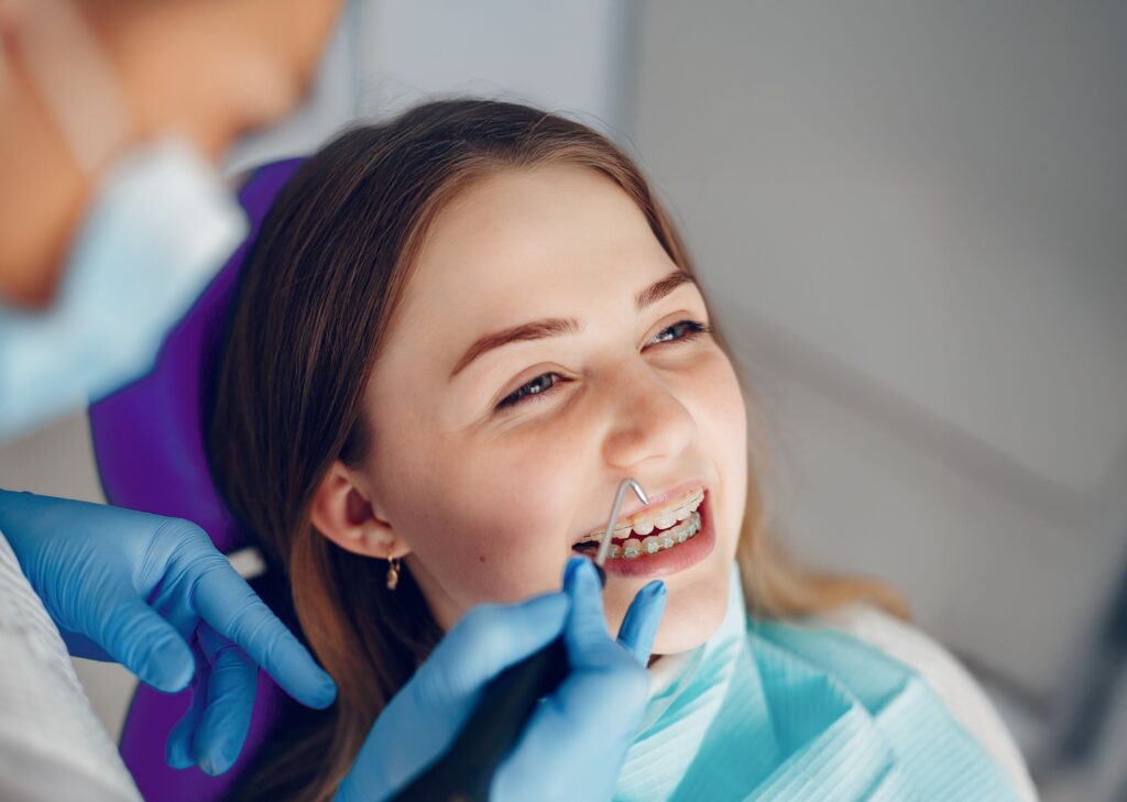 Teen laughing while having her braces fixed by her orthodontist