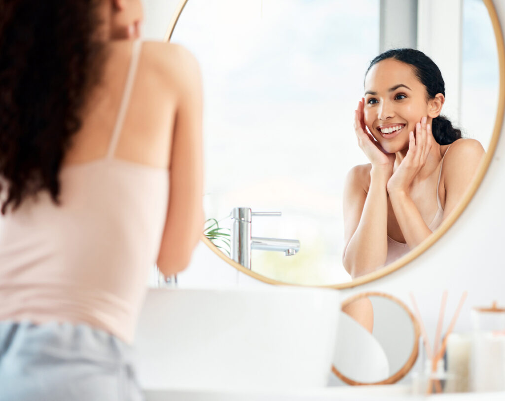 Woman holding her face as she admires her new smile in the mirror.