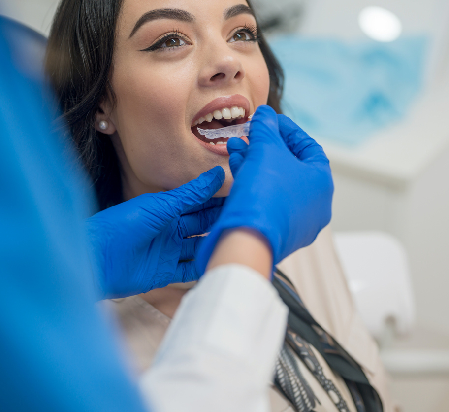 Orthodontic technician inserting and Invisalign aligner into the mouth of an adult patient