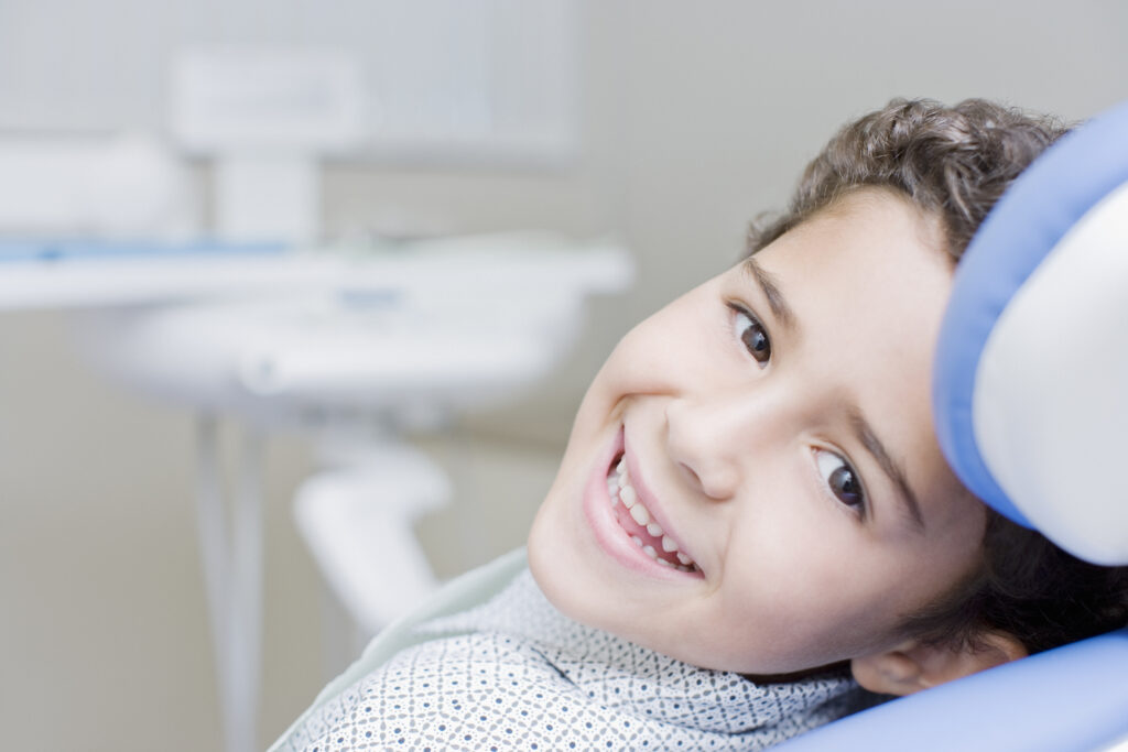 A boy sitting in a dental chair, smiling.